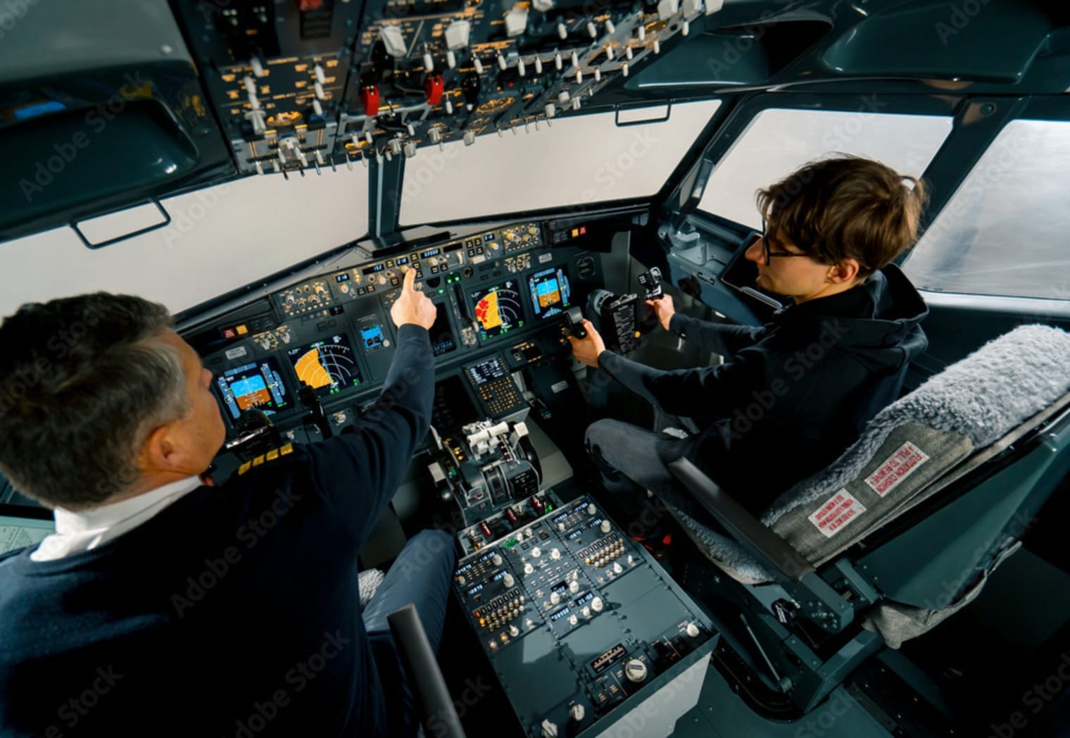 Photograph of An experienced pilot instructs a young student before a training flight in the cockpit of an aero simulator Stock Photo