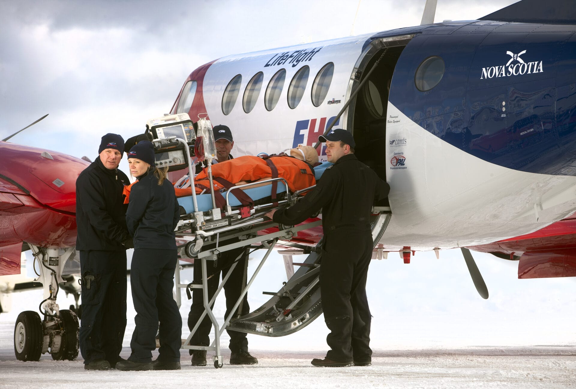 Paramedics loading a mannequin on a stretcher onboard a Beechcraft 1900 air ambulance